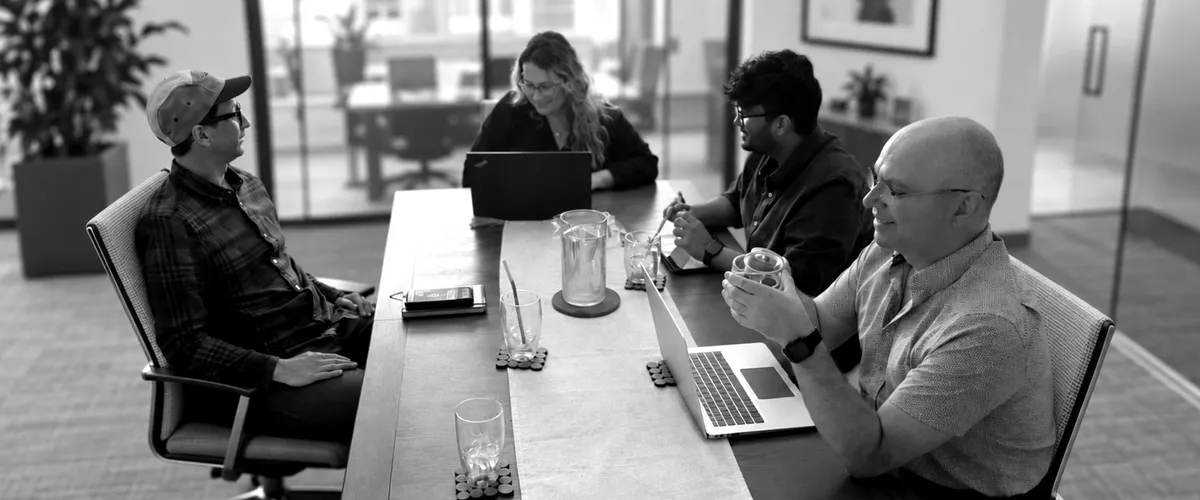 Four colleagues collaborating around a conference table